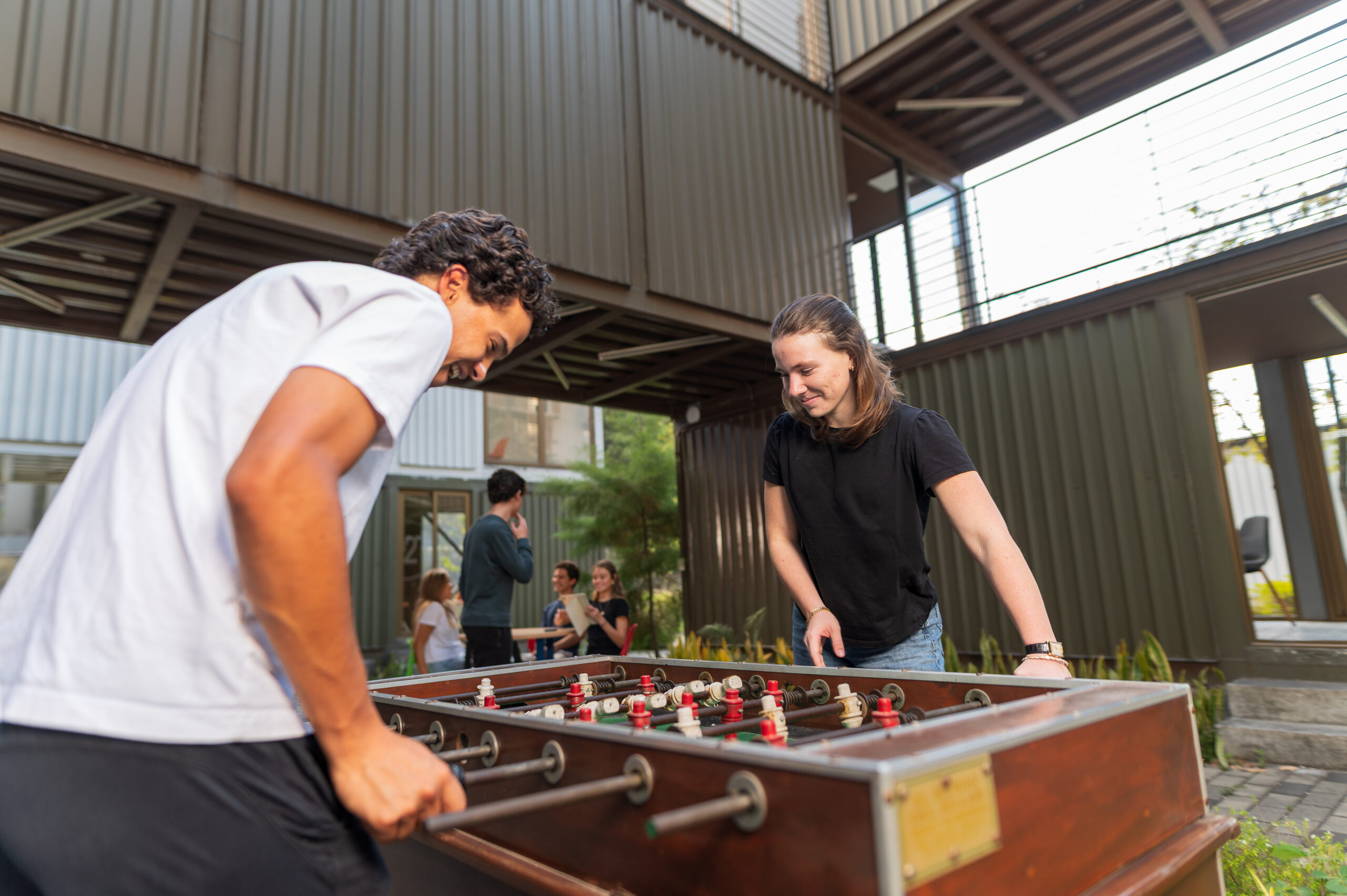 Dos estudiantes universitarios jugando futbolito de mesa en las áreas comunes al aire libre de D15 Dorms.